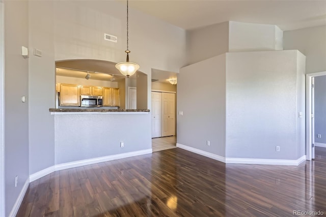 unfurnished living room featuring dark hardwood / wood-style floors and a towering ceiling