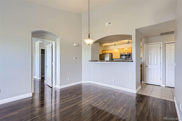 unfurnished living room featuring dark wood-type flooring and a high ceiling