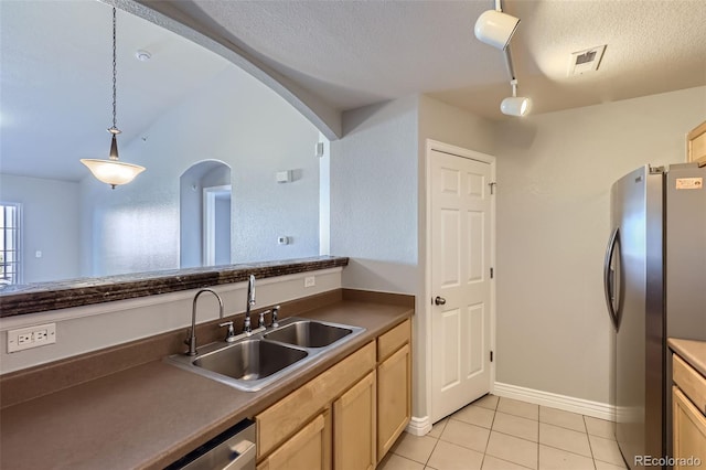 kitchen with light tile patterned flooring, sink, a textured ceiling, stainless steel refrigerator, and pendant lighting