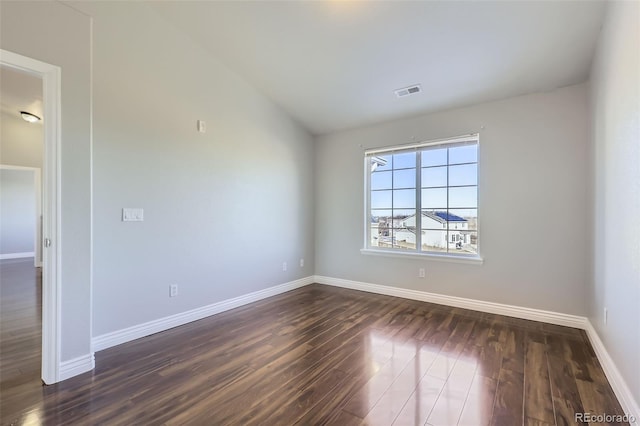 unfurnished room featuring lofted ceiling and dark wood-type flooring