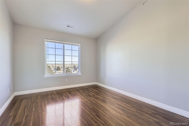 spare room with lofted ceiling and dark wood-type flooring