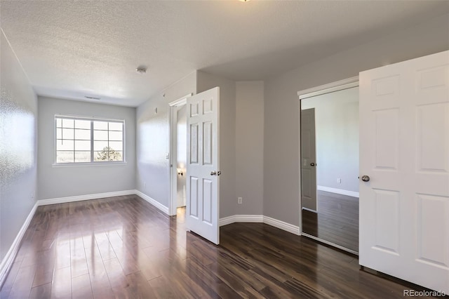 unfurnished bedroom featuring dark wood-type flooring, a closet, and a textured ceiling