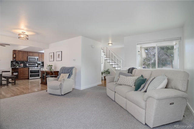 living room featuring light colored carpet, stairs, and baseboards