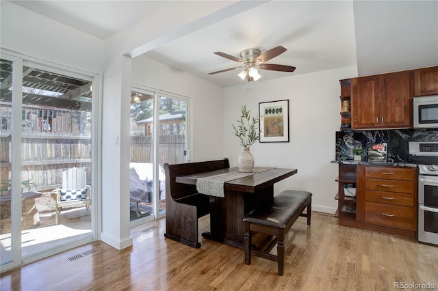 dining room featuring visible vents, a ceiling fan, baseboards, and light wood finished floors