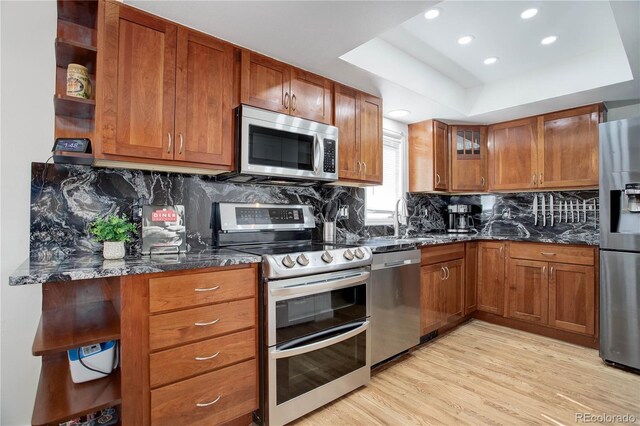 kitchen featuring open shelves, dark stone countertops, a raised ceiling, and stainless steel appliances