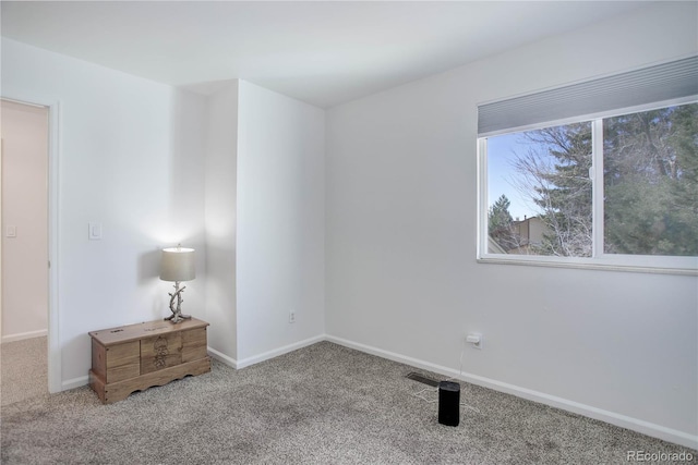 carpeted spare room with visible vents and baseboards