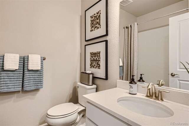 bathroom featuring curtained shower, vanity, and toilet