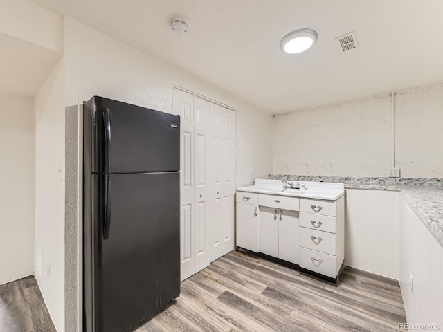 2102 S Pearl St, Denver, CO 80210 - kitchen with freestanding refrigerator, light wood-style floors, light countertops, and white cabinets