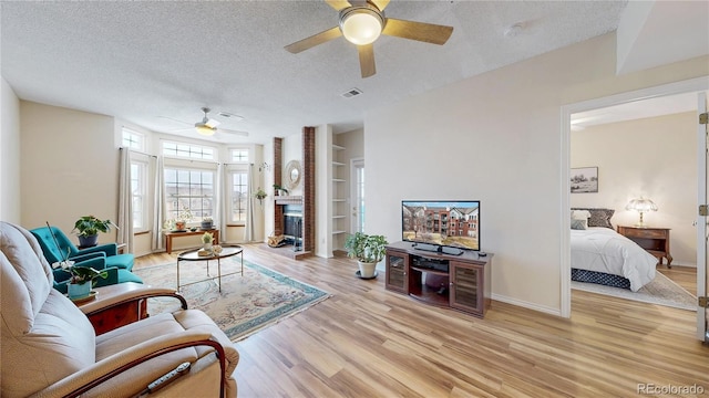 living room with built in features, a brick fireplace, a textured ceiling, light wood-type flooring, and baseboards