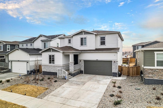 craftsman-style home with fence, a residential view, an attached garage, stone siding, and driveway