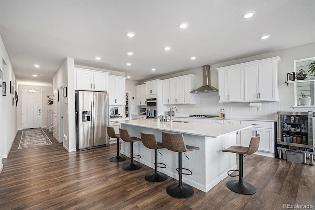 kitchen featuring a sink, wall chimney exhaust hood, stainless steel appliances, recessed lighting, and wine cooler