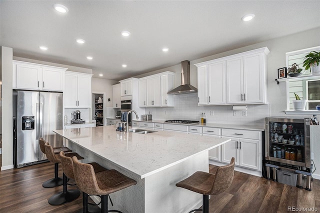 kitchen with wall chimney range hood, a sink, beverage cooler, stainless steel appliances, and dark wood-type flooring