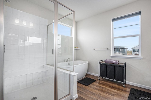 full bathroom featuring a freestanding tub, baseboards, a stall shower, and wood finished floors