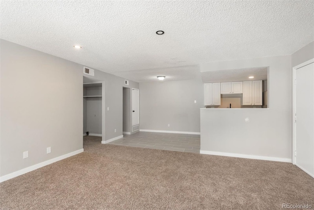 18071 E Kentucky Ave Unit 203, Aurora, CO 80017 - unfurnished living room featuring light colored carpet, a textured ceiling, recessed lighting, baseboards, and light tile patterned flooring