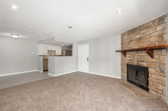 18071 E Kentucky Ave Unit 203, Aurora, CO 80017 - unfurnished living room with carpet floors, a stone fireplace, a textured ceiling, and baseboards