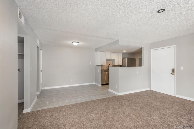 18071 E Kentucky Ave Unit 203, Aurora, CO 80017 - unfurnished living room with light colored carpet, a textured ceiling, baseboards, and a sink
