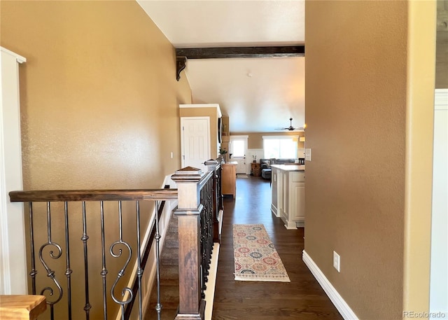 corridor with lofted ceiling with beams, dark wood-style flooring, and baseboards