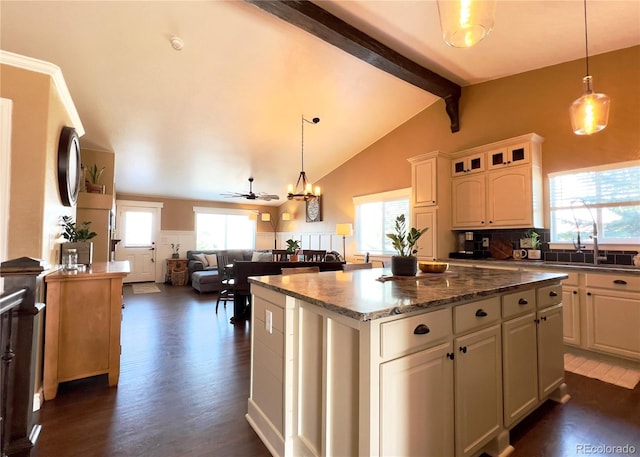 kitchen featuring a center island, dark wood-style flooring, vaulted ceiling with beams, hanging light fixtures, and a sink