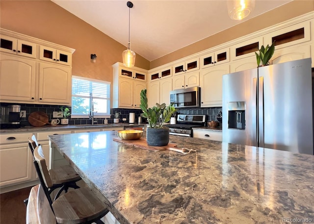 kitchen featuring appliances with stainless steel finishes, lofted ceiling, hanging light fixtures, and backsplash