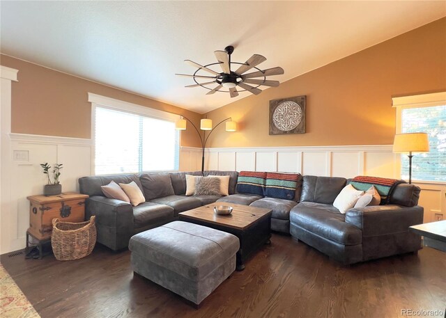 living room with lofted ceiling, a decorative wall, a wainscoted wall, dark wood-style flooring, and a ceiling fan