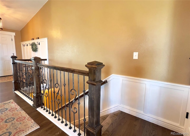 stairs featuring a wainscoted wall, vaulted ceiling, and wood finished floors