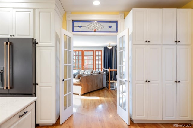 kitchen featuring white cabinetry, high end refrigerator, light hardwood / wood-style floors, light stone countertops, and french doors