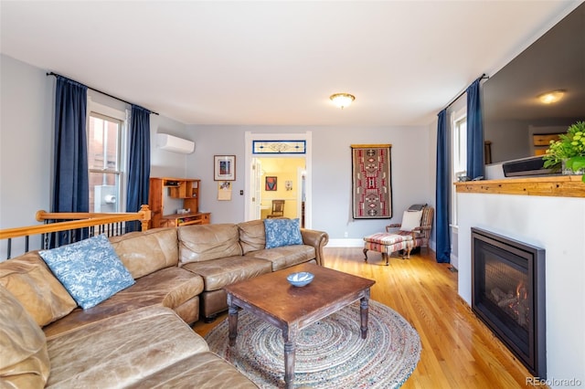 living room featuring a wall mounted air conditioner and light hardwood / wood-style flooring