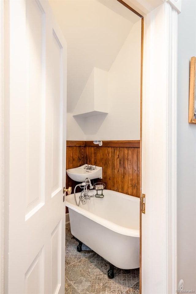 bathroom featuring a tub, sink, and wooden walls