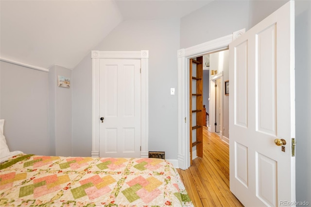 bedroom with lofted ceiling and light wood-type flooring