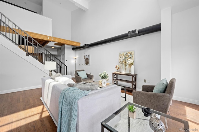 living area featuring baseboards, stairs, a high ceiling, and wood finished floors