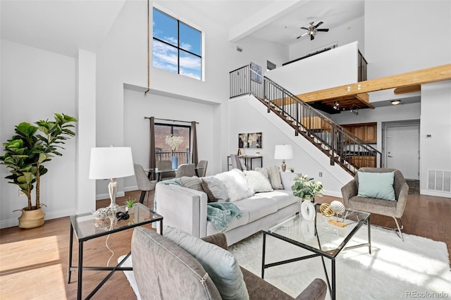 living area featuring baseboards, wood finished floors, stairway, and a towering ceiling