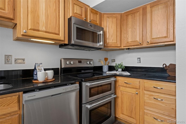 kitchen with a sink, dark countertops, and stainless steel appliances