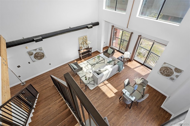 living room with wood finished floors, baseboards, and a high ceiling