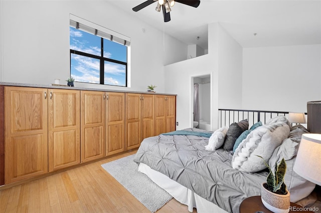 bedroom featuring ceiling fan, ensuite bathroom, and light wood-style flooring