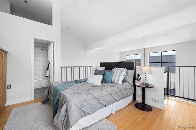 bedroom with baseboards, ensuite bathroom, and wood finished floors