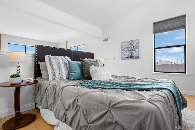 bedroom with baseboards, multiple windows, and wood finished floors
