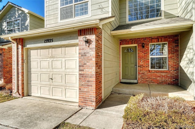 entrance to property with a garage, a shingled roof, and brick siding