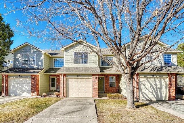 view of front of home with a front lawn, brick siding, driveway, and an attached garage