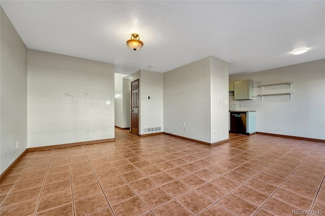 spare room with light tile patterned floors, a sink, visible vents, and baseboards