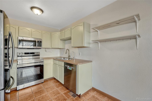 kitchen featuring open shelves, stainless steel appliances, light countertops, a sink, and tile patterned flooring