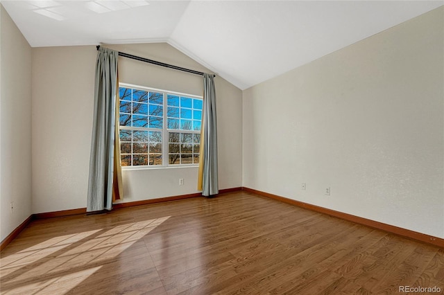 empty room with vaulted ceiling, wood finished floors, and baseboards