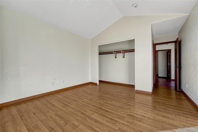 unfurnished bedroom with lofted ceiling, a closet, baseboards, and wood finished floors