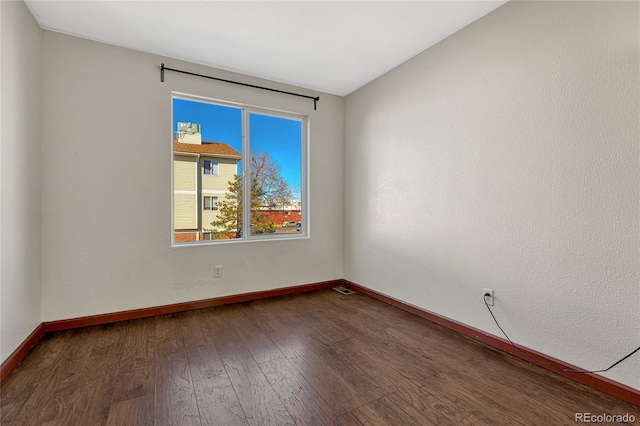 unfurnished room with dark wood-type flooring and baseboards