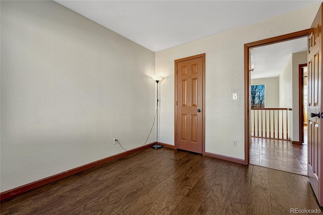 unfurnished room with baseboards and dark wood finished floors