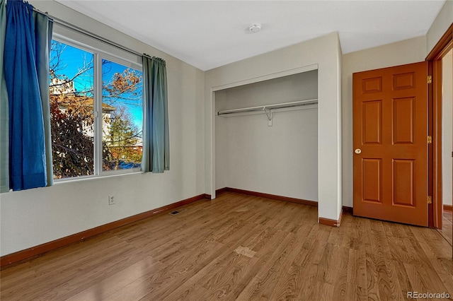 unfurnished bedroom with baseboards, a closet, visible vents, and light wood-style floors