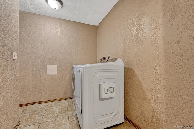 laundry area with washer / clothes dryer, light tile patterned floors, a textured wall, and laundry area