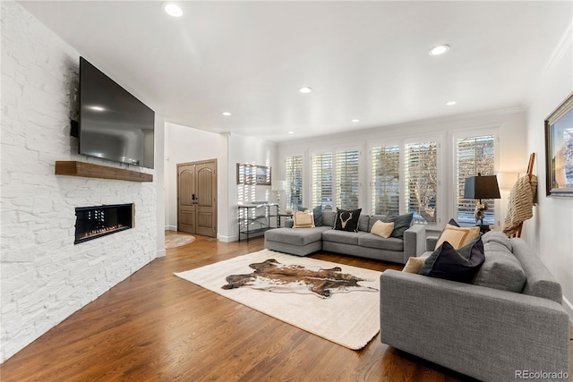 living room featuring hardwood / wood-style flooring, ornamental molding, and a fireplace