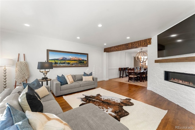 living room featuring a fireplace, crown molding, a chandelier, and hardwood / wood-style floors