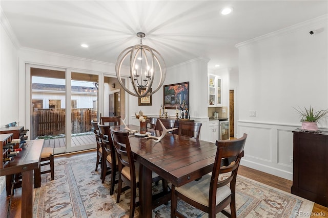 dining area with hardwood / wood-style floors, crown molding, and a notable chandelier