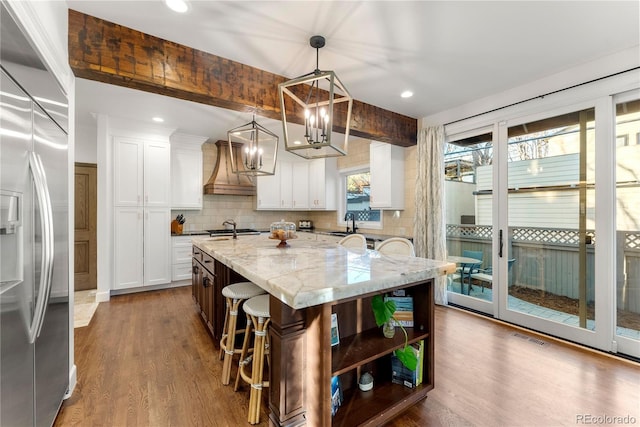 kitchen featuring white cabinetry, pendant lighting, built in fridge, and a center island